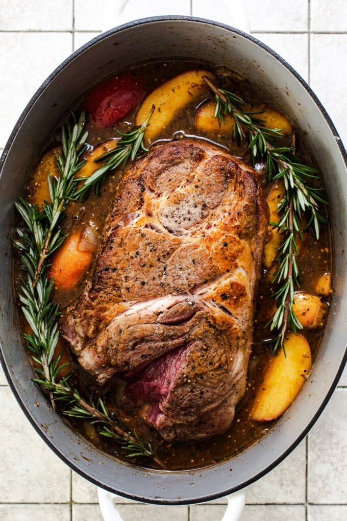 pork shoulder with apples and herbs in large pot