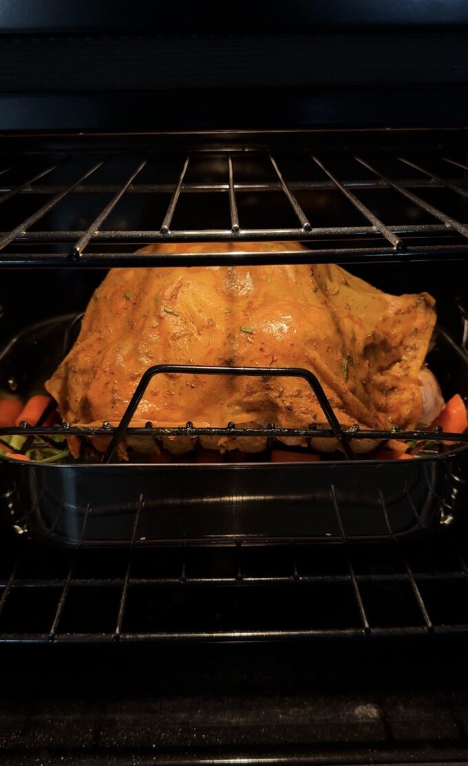 turkey with cheesecloth in roasting pan in the oven