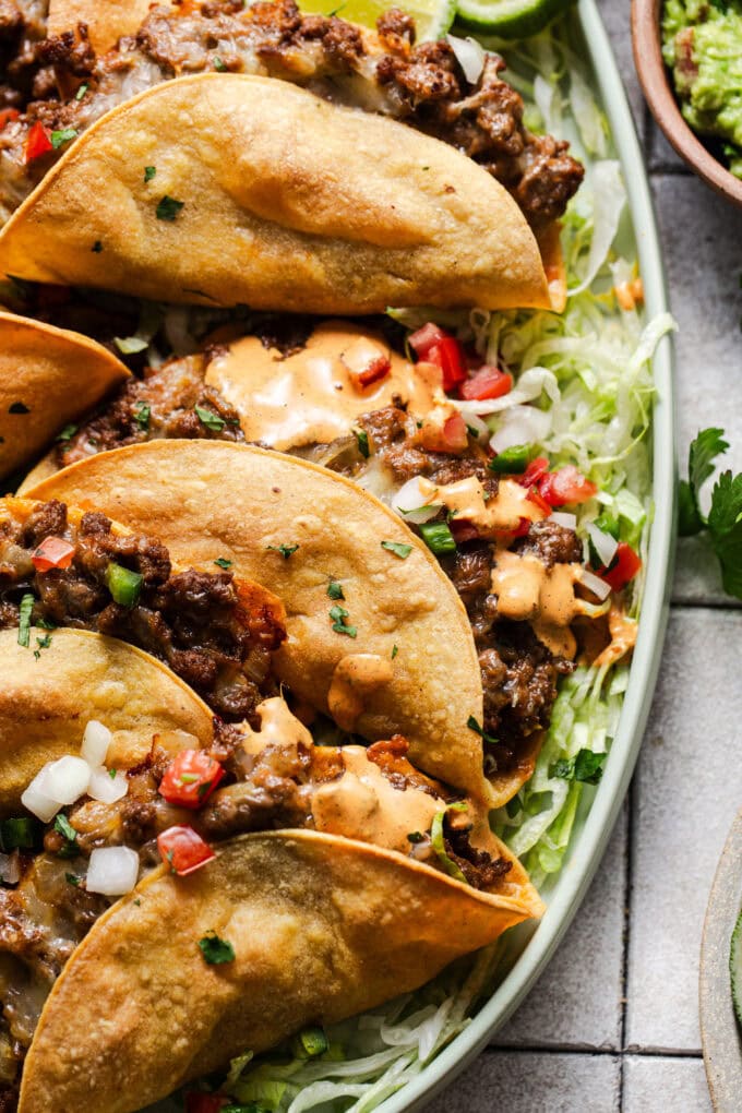ground beef tacos on top of shredded lettuce on platter
