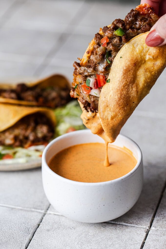 hand dipping ground beef taco in chipotle ranch sauce