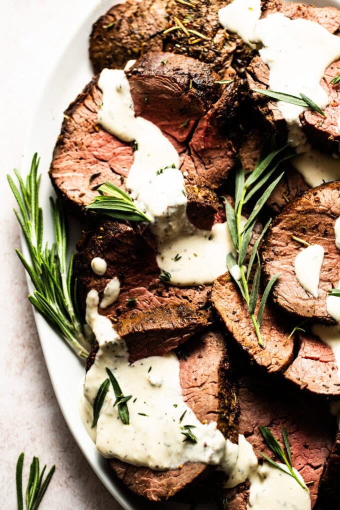 sliced beef tenderloin on platter with horseradish cream sauce