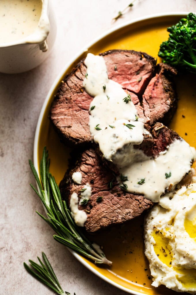 beef tenderloin with horseradish cream sauce on yellow plate