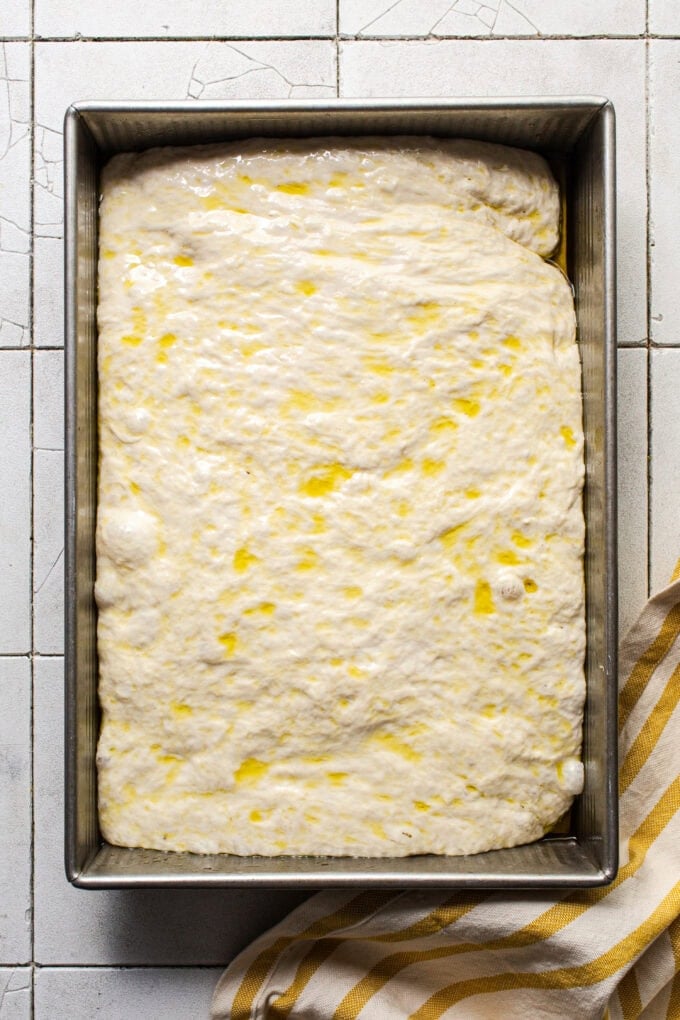 proofed focaccia dough in pan with oil