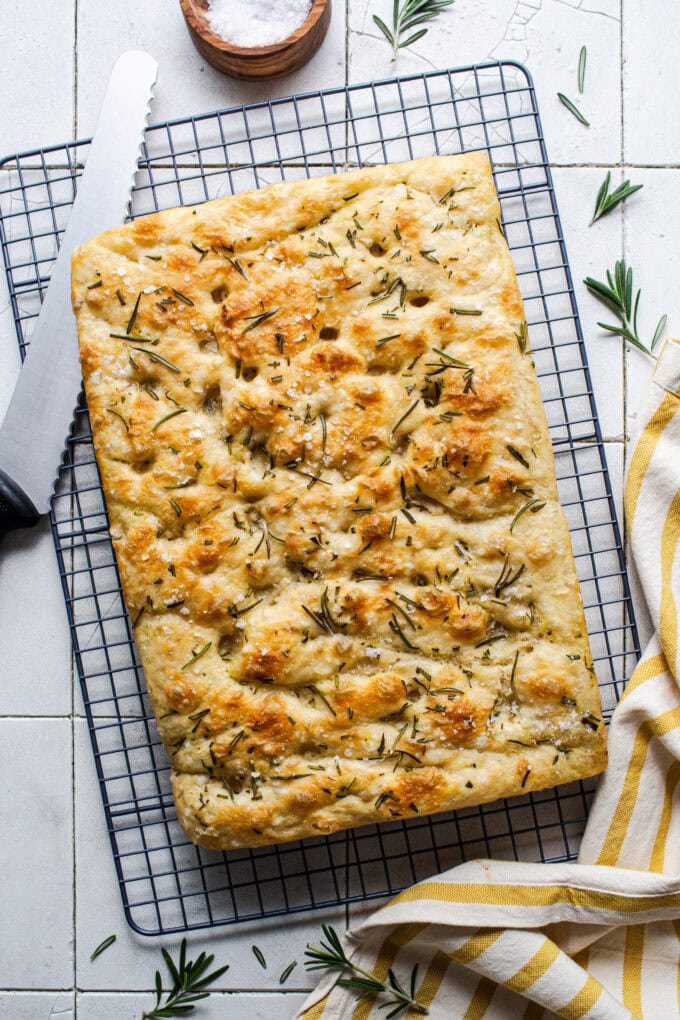 baked focaccia bread on wire rack with knife
