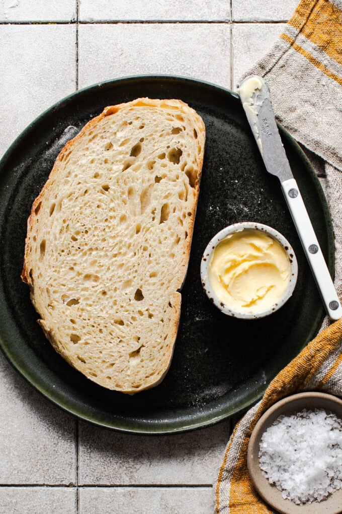 slice of no knead bread on plate with butter