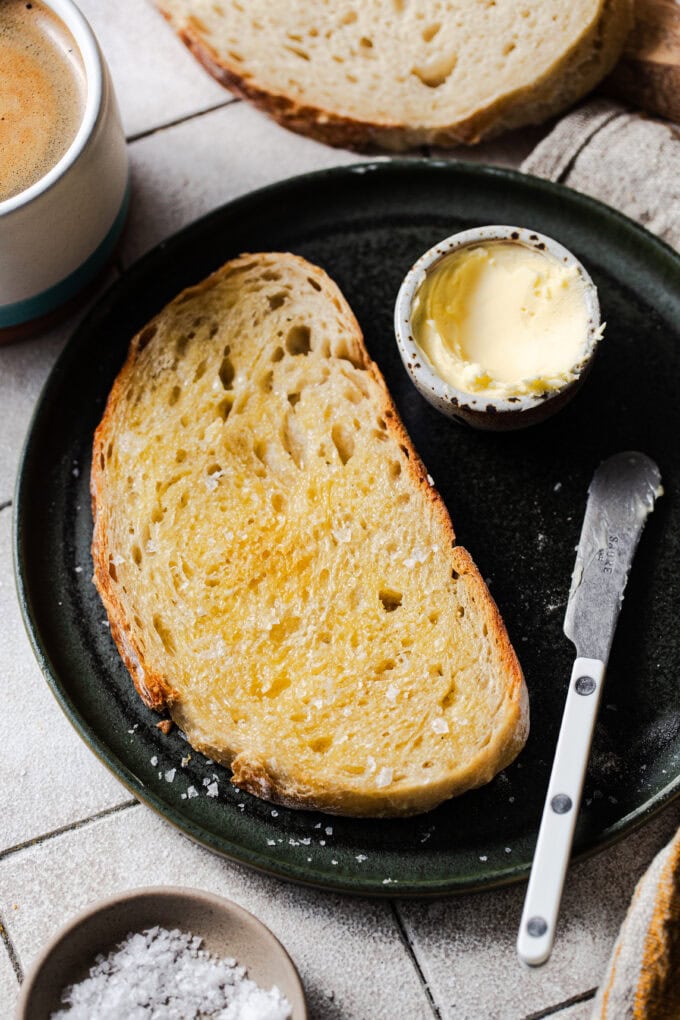 buttered bread on black plate with butter knife