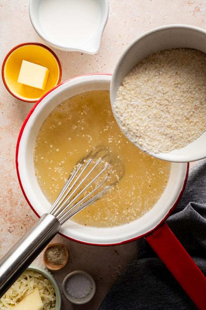white grits being poured into saucepan with whisk