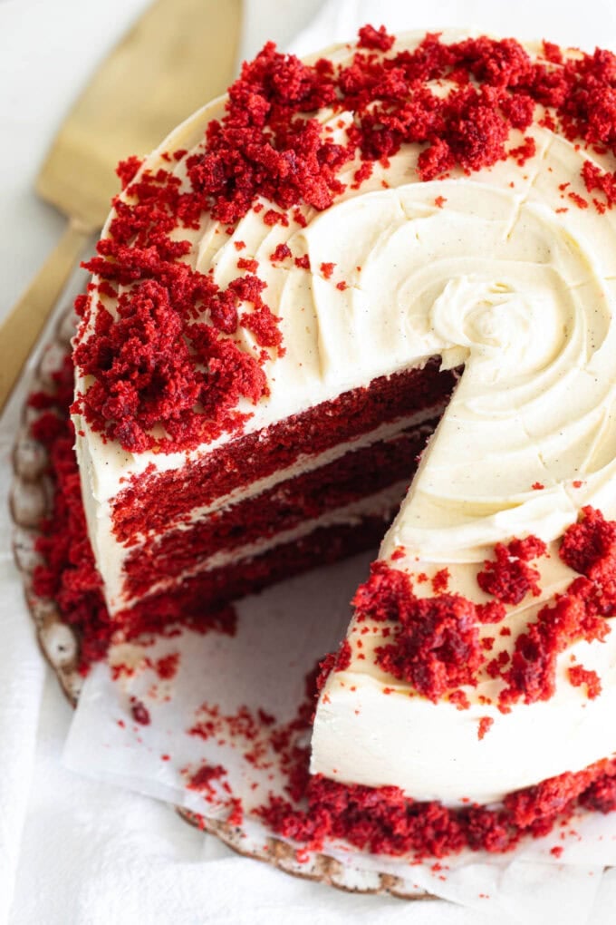 sliced red velvet layer cake on platter with gold cake knife