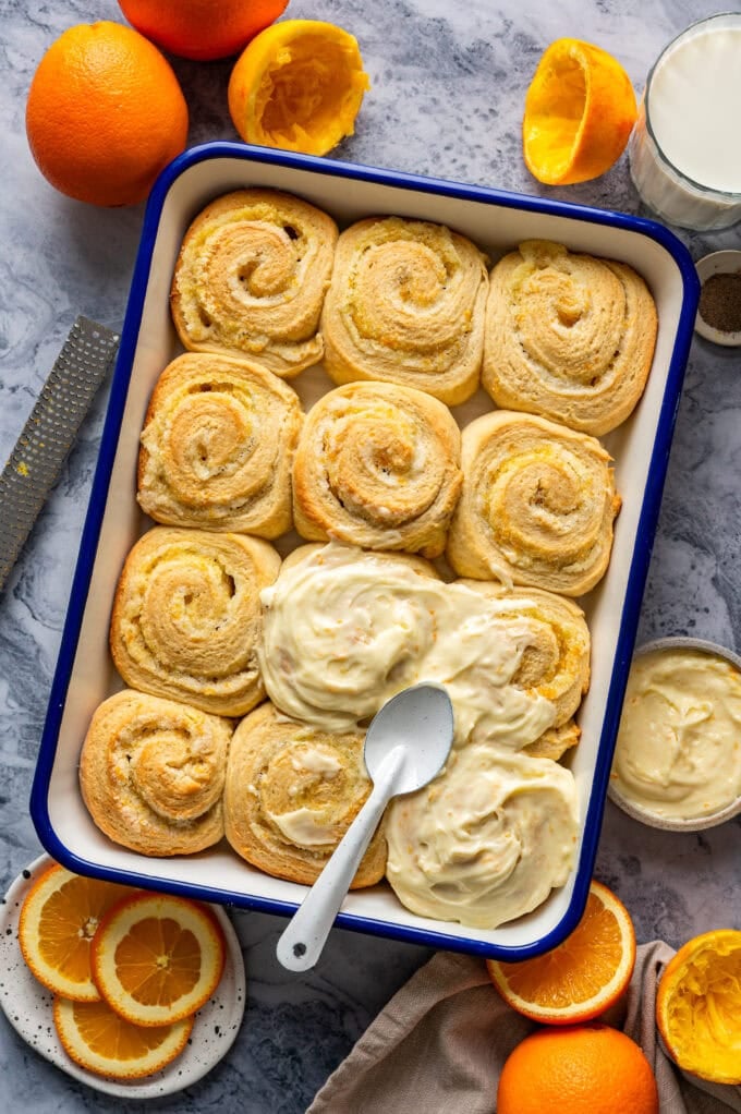 partially frosted orange sweet rolls in baking pan