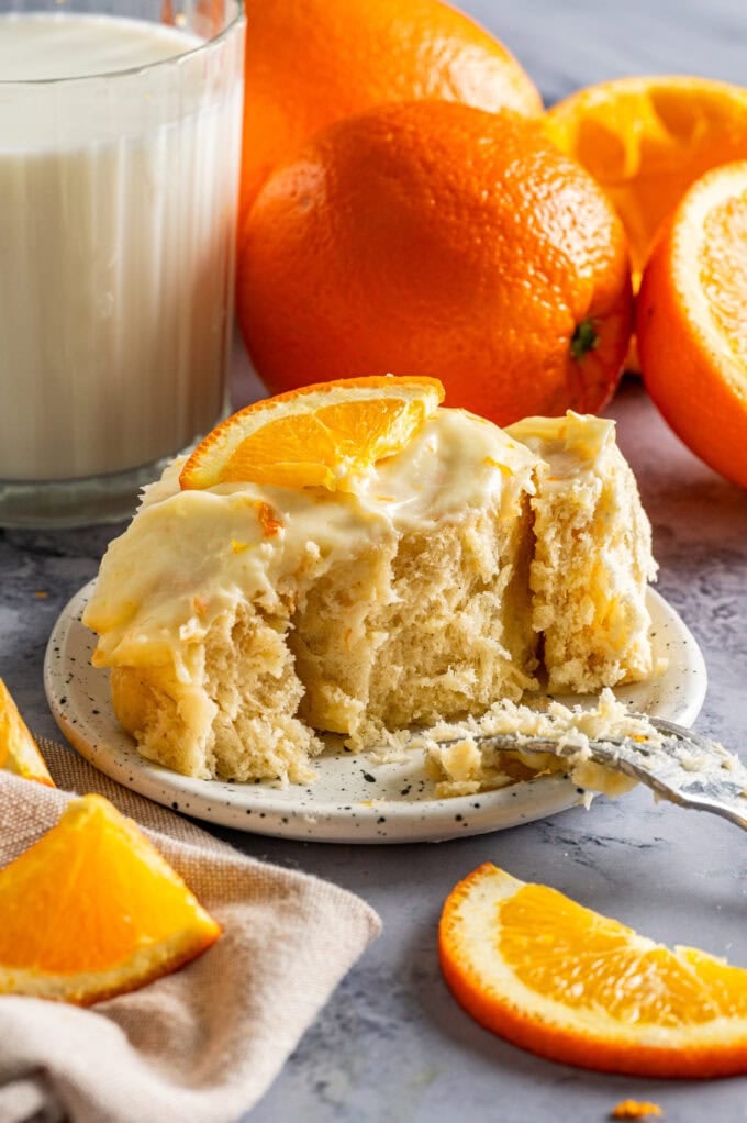 fluffy orange sweet roll with fork on small plate