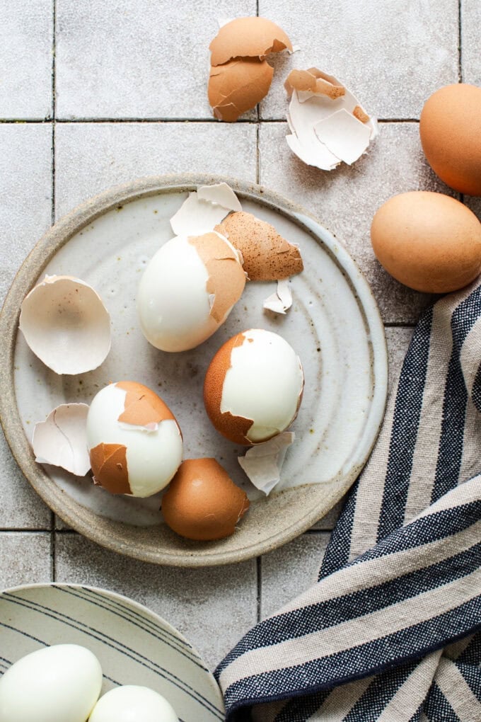half peeled hard boiled eggs on small plate