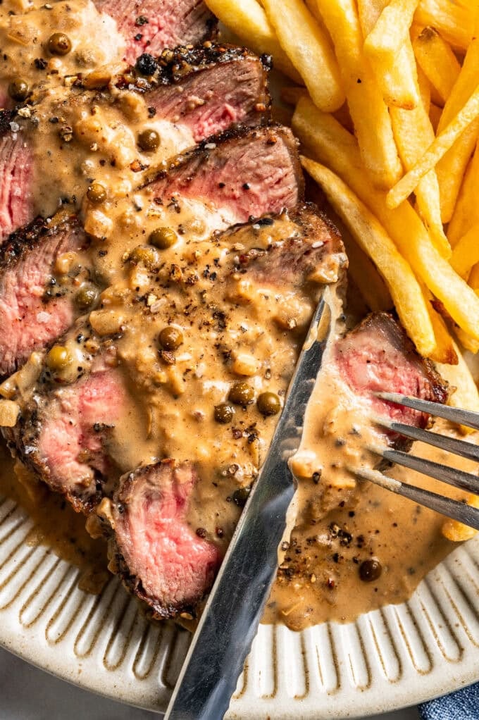 closeup of steak au poivre with fork and knife