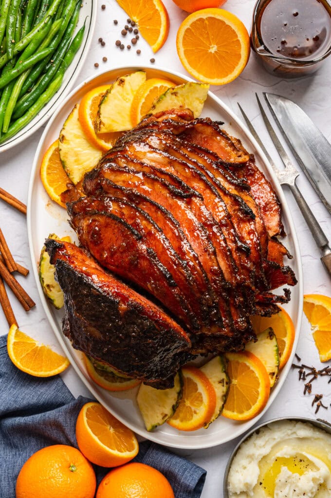 spiral glazed ham on platter with orange and pineapple slices