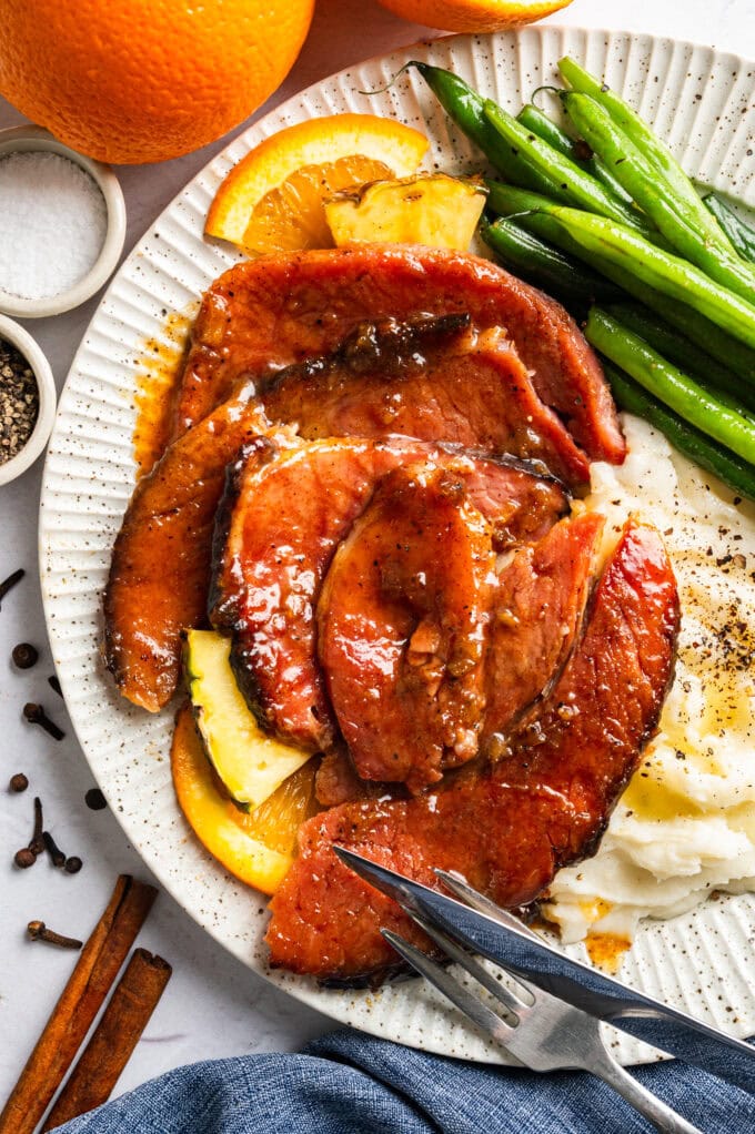 glazed ham slices on plate with mashed potatoes and green beans