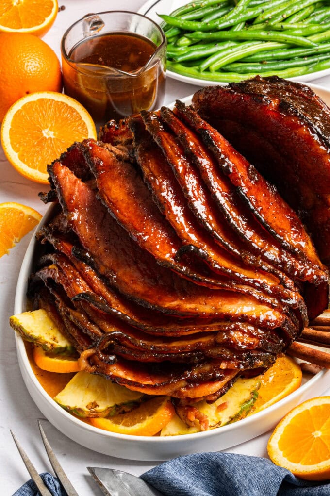 sliced glazed ham on platter with oranges