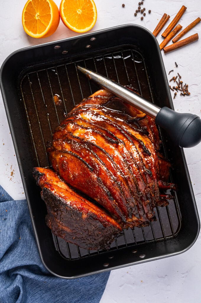 glazed ham in baking pan with basting tool on the side