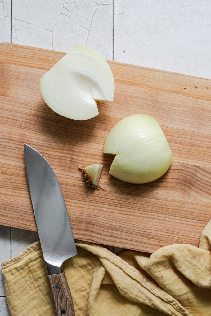 root end of onion cut off on cutting board with knife