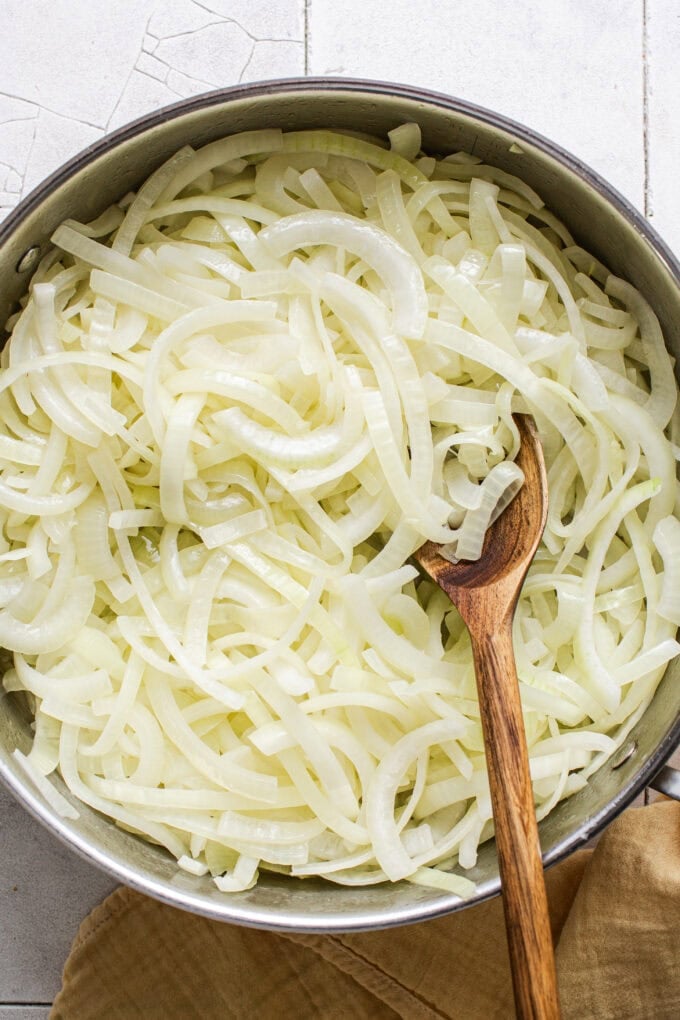 yellow onions in large pot with wooden spoon