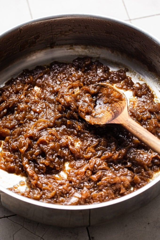 deeply golden caramelized onions in pot with wooden spoon