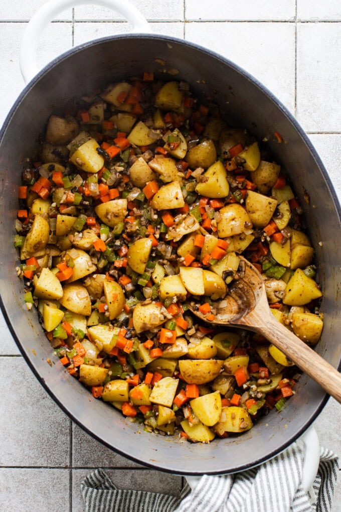 sautéed veggies in large pot with wooden spoon
