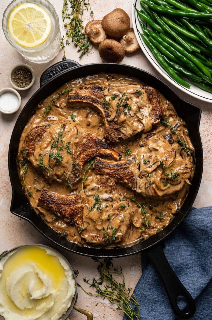 smothered pork chops with mushroom gravy in skillet