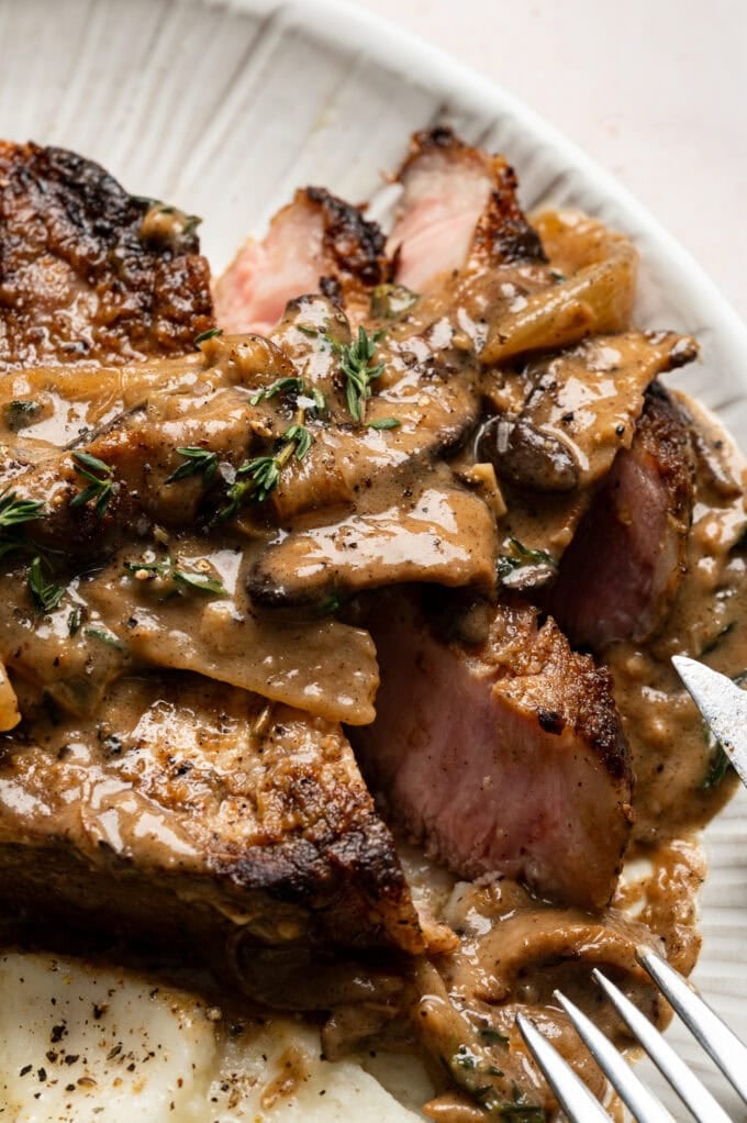 sliced pork chop with mushroom gravy in plate