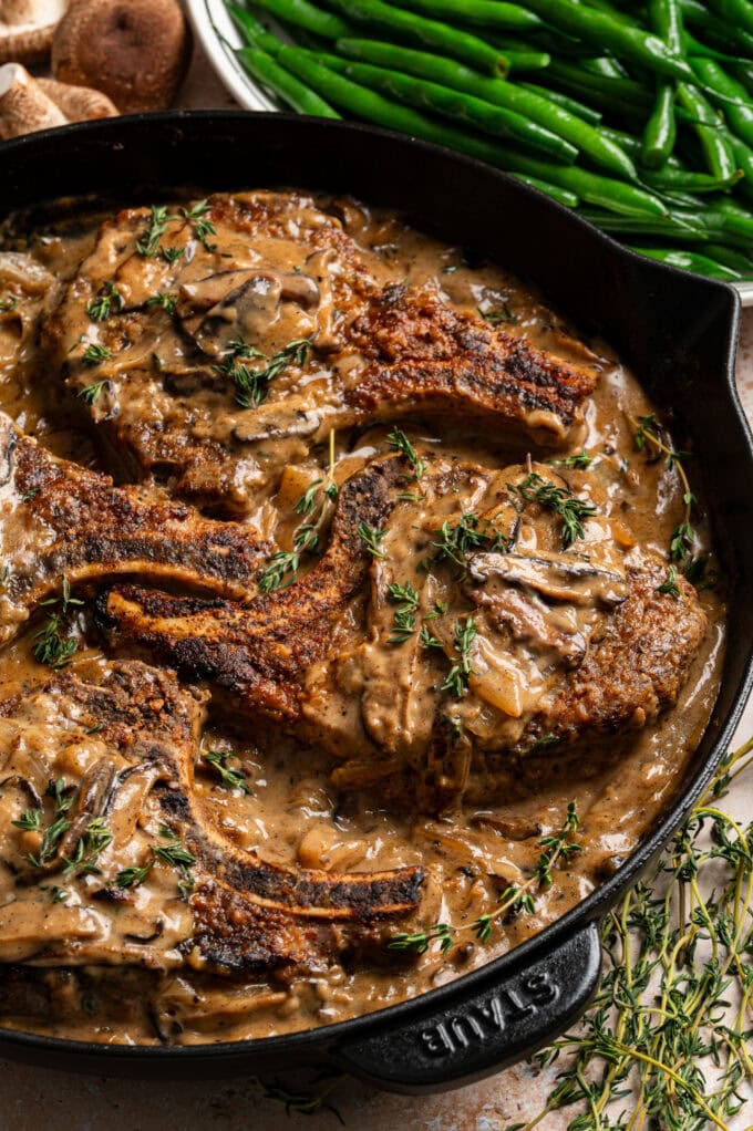 closeup of pork chops with mushroom gravy in skillet