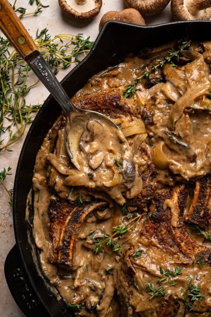spoon pouring mushroom gravy over pork chops