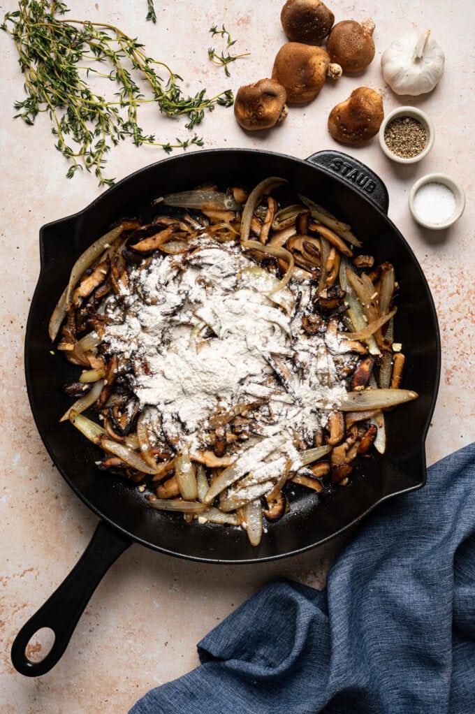 flour in skillet with sautéed mushrooms