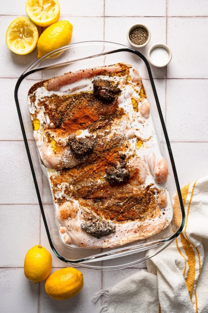 raw chicken in glass dish with spices