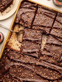 sliced cola cake in sheet pan with serving utensil