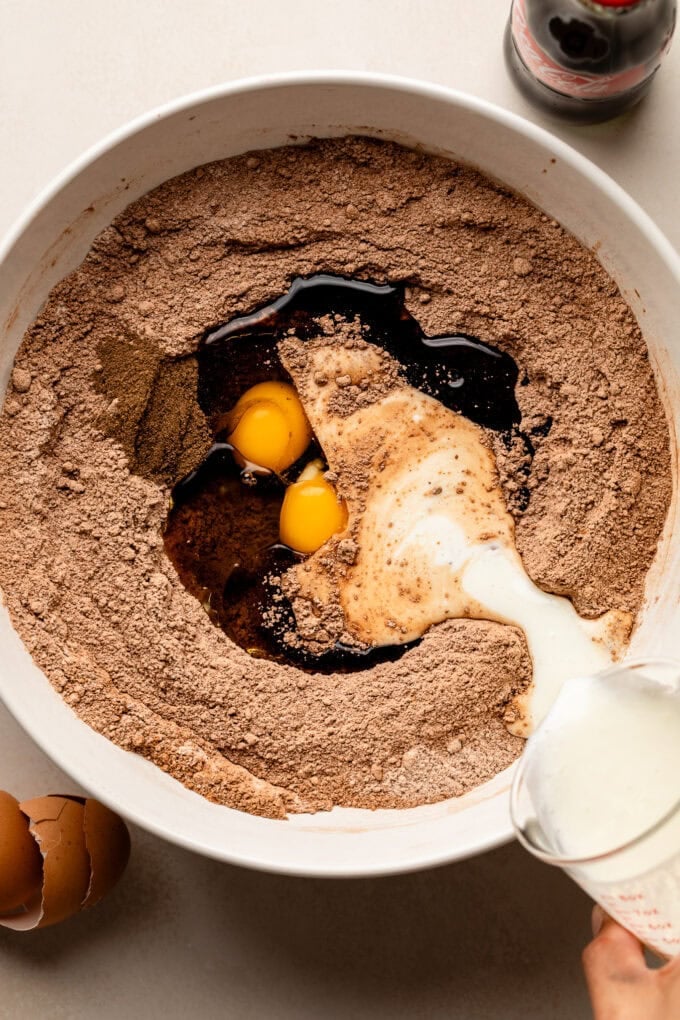 chocolate cake ingredients in large bowl with milk being poured