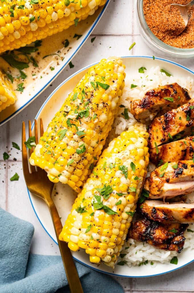 creamy corn on the cob and grilled chicken on plate