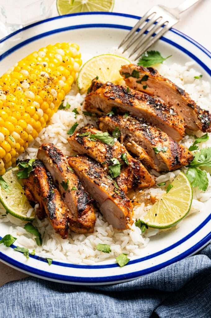 sliced grilled chicken with rice and corn on plate