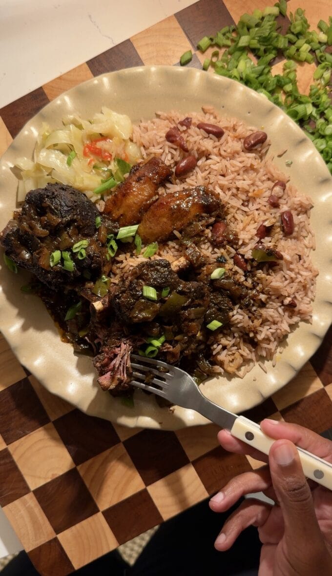black hand with fork on plate with braised short ribs and rice