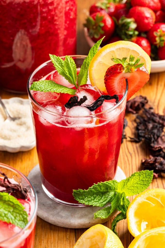 strawberry hibiscus lemonade in glass on white coaster