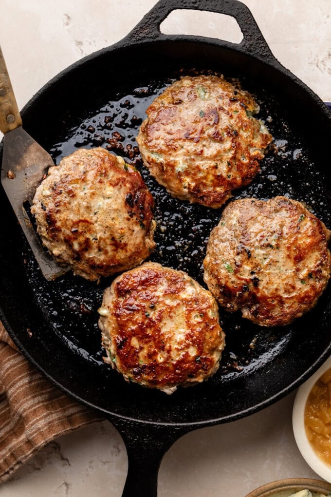seared burger patties in skillet with spatula