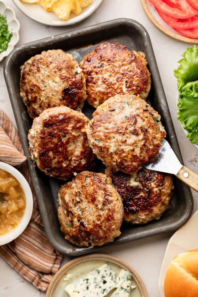 seared turkey burgers with spatula on baking sheet