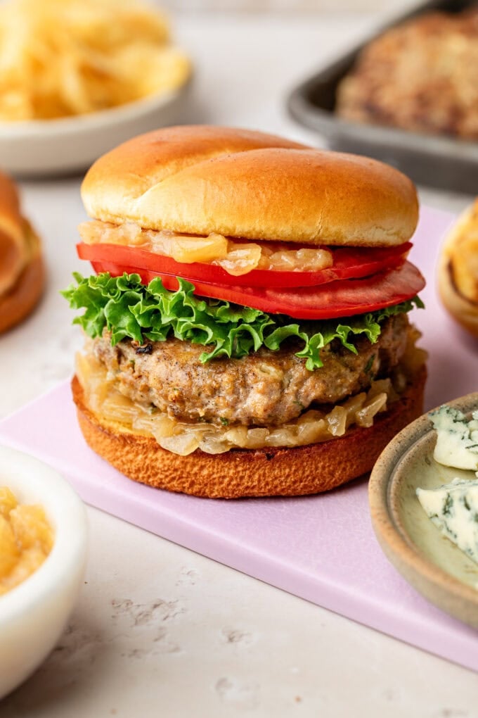 blue cheese turkey burgers with lettuce and tomato on purple cutting board