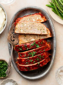 zucchini feta meatloaf sliced on silver platter with serving utensil