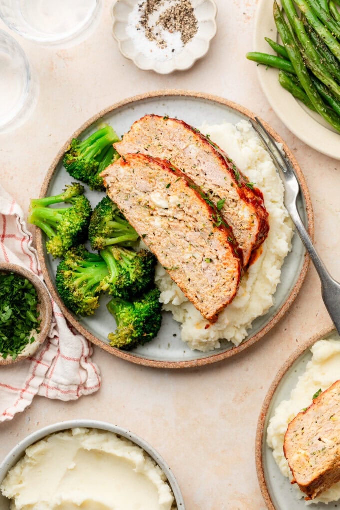sliced zucchini feta meatloaf with mashed potatoes and broccoli on plate