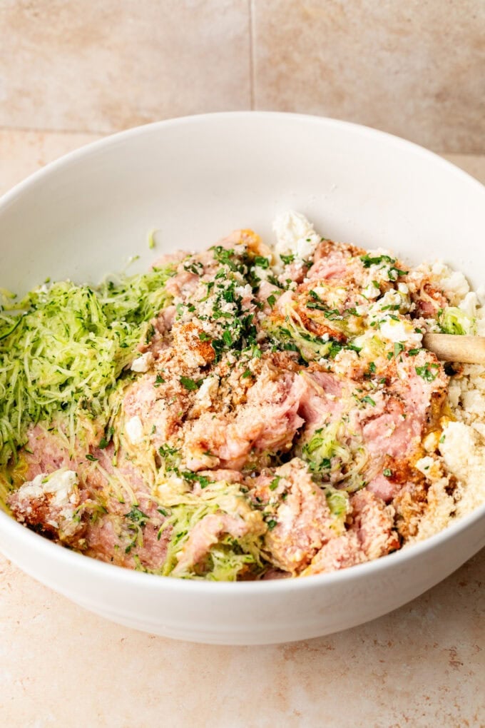raw ground chicken with shredded zucchini in large bowl