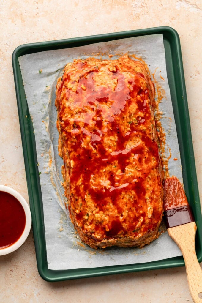 raw meatloaf on baking sheet with bbq sauce