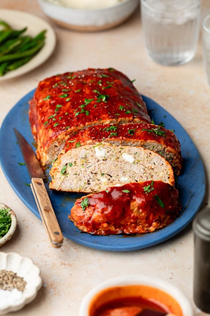 zucchini feta meatloaf on blue platter with knife