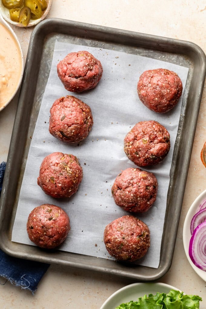 raw ground beef balls on baking sheet