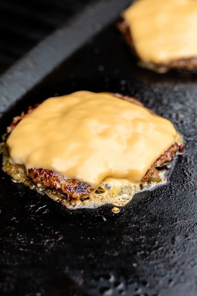 smash burger with cheese on griddle