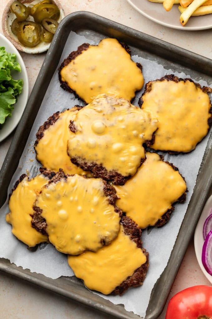 smash burgers with cheese on baking sheet