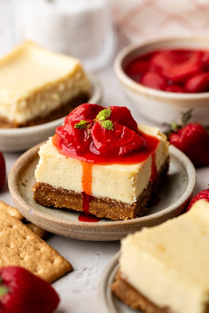 vanilla cheesecake bar with strawberry compote and mint sprig on plate