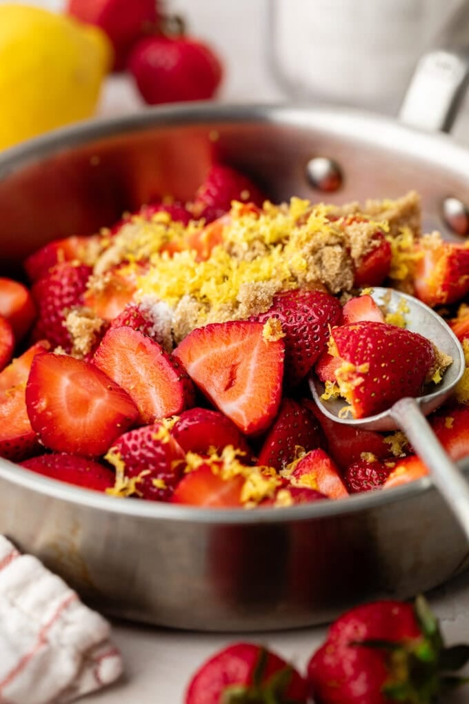 strawberry compote ingredients in saucepan with spoon