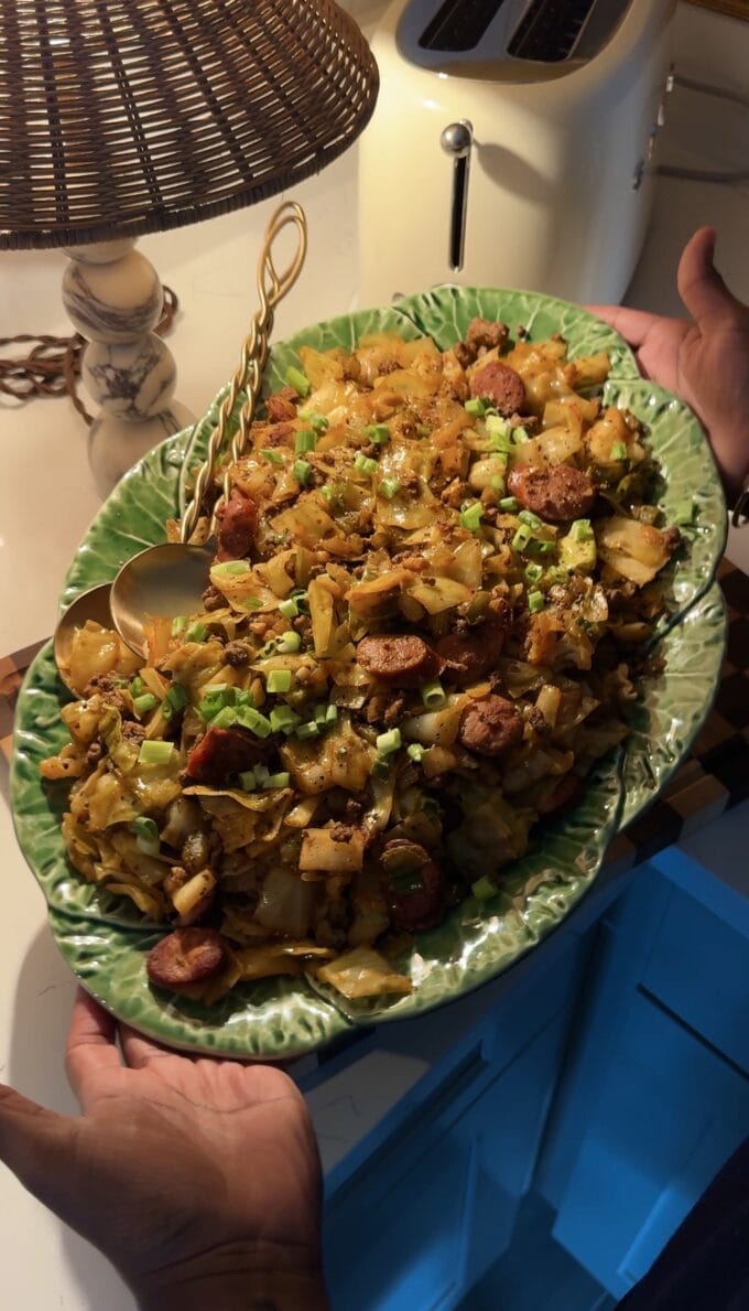 black hands holding green platter with dirty cabbage